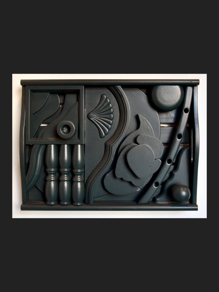 Abstract wall sculpture made from reclaimed wood featuring various carved geometric shapes and patterns arranged in a dynamic design by David Furman