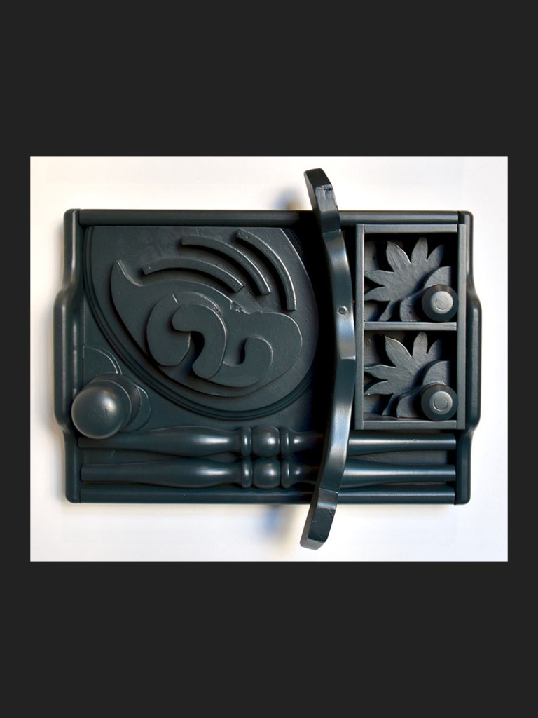 A decorative wall sculpture featuring abstract shapes, waves, and floral elements, made from reclaimed wood by David Furman