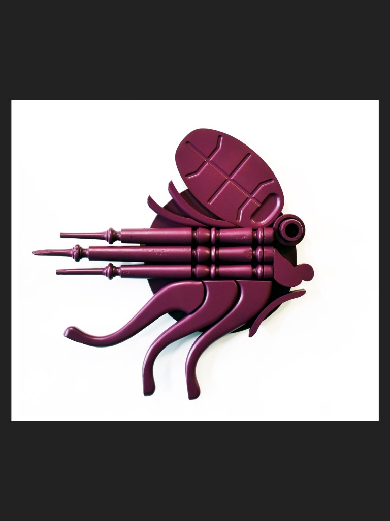 A stylized fish made from reclaimed wood, painted a deep purple and featuring multiple tentacle-like extensions and a rounded head by David Furman