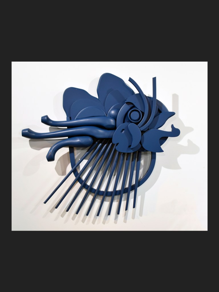 A sculptural piece made from reclaimed wood featuring a stylized fish design, painted in deep blue by David Furman
