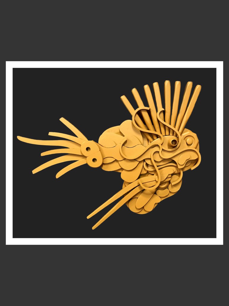 A stylized yellow fish sculpture made from reclaimed wood of abstract shapes against a black background by David Furman