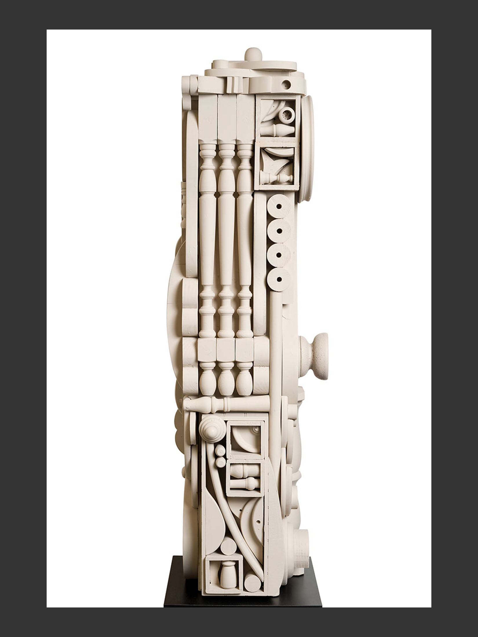 A side view of a totem sculpture made from reclaimed wood details featuring various geometric shapes and forms, crafted in a neutral color and mounted on a black base by David Furman