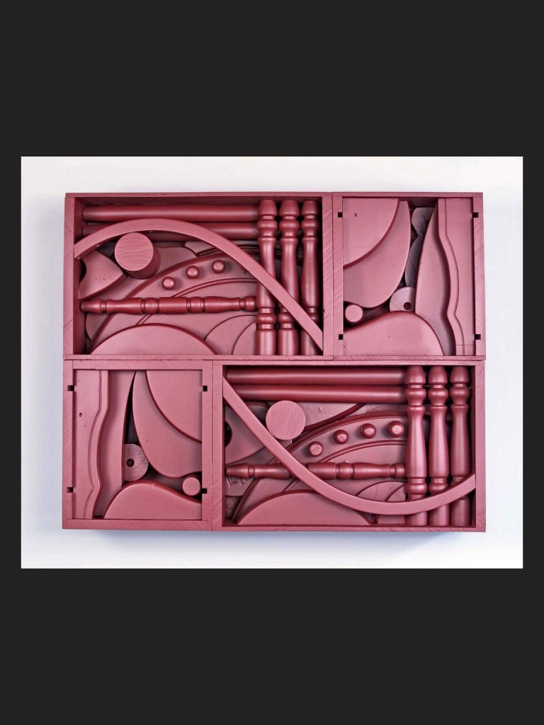 A wall sculpture made from reclaimed wood that is an arrangement of red sculptural shapes featuring various rounded and linear designs within a rectangular frame by David Furman