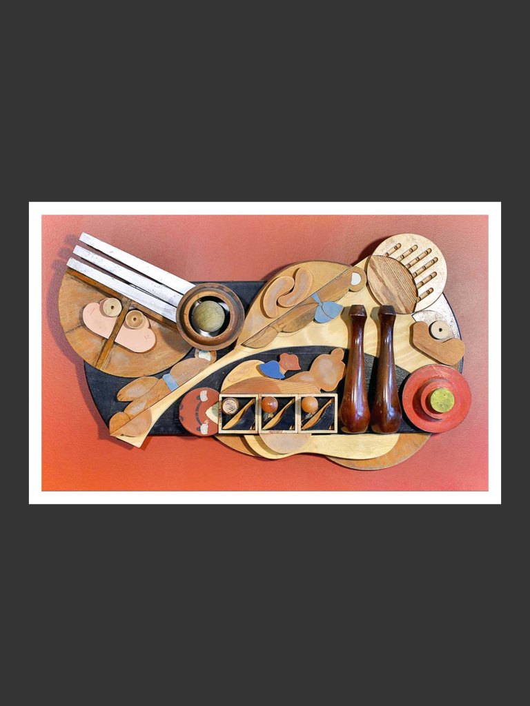 Abstract artistic wall sculpture made from recovered wooden pieces featuring various shapes and utensils arranged creatively against a colored background by David Furman