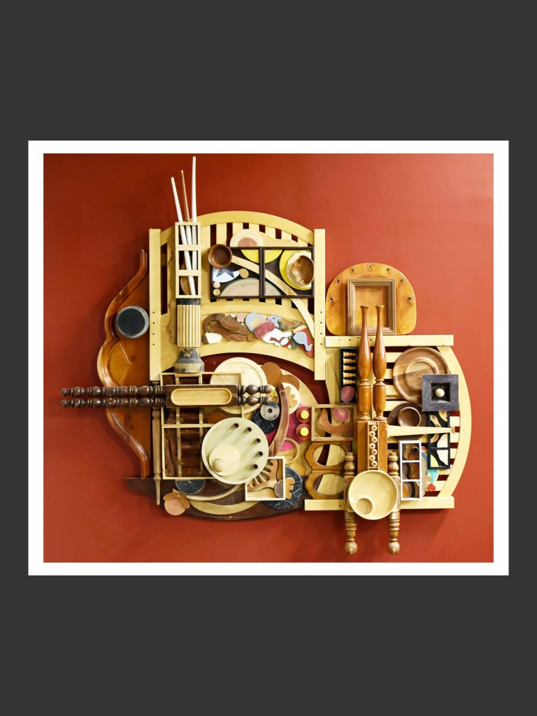 A colorful wooden wall sculpture art piece made out of reclaimed wooden elements composed of various shapes, textures, and colors, featuring geometric patterns and organic forms by David Furman