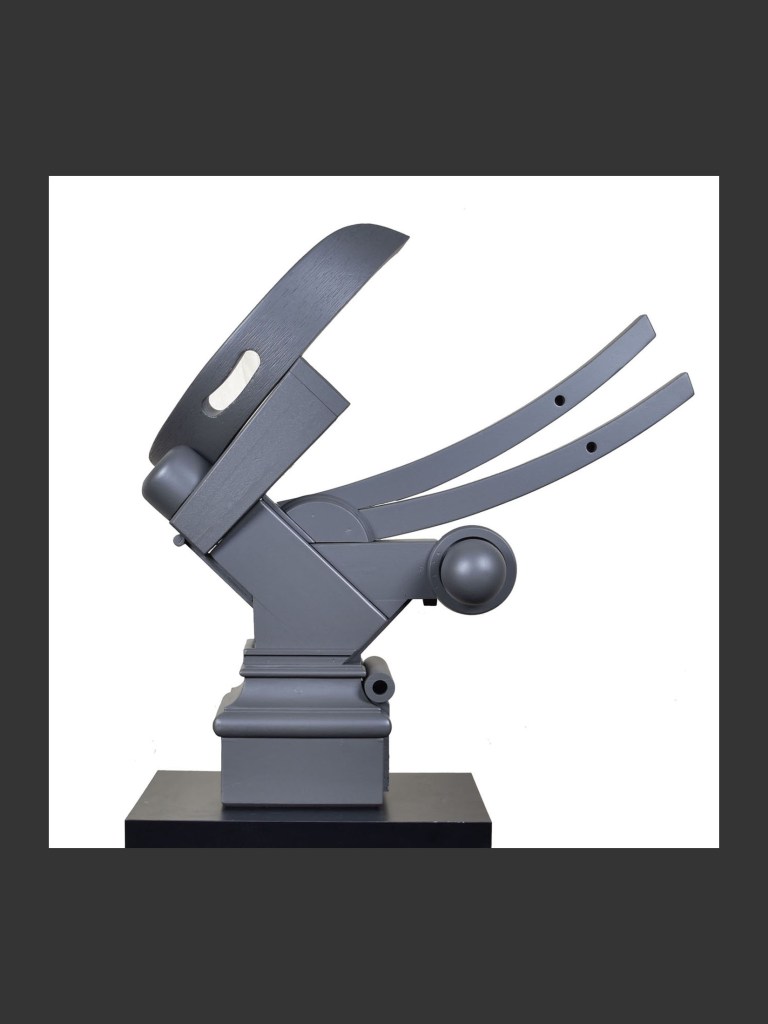 An abstract sculpture made from reclaimed wood composed of dynamic geometric forms and  painted gray and mounted on a black pedestal by David Furman.