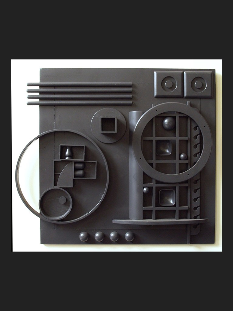 Abstract wall sculpture artwork made from reclaimed wooden elements featuring various geometric shapes in black, including circles, squares, and lines, arranged on a flat surface by David Furman