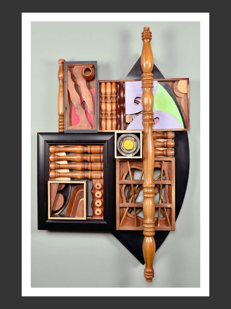 A wall-mounted sculpture made from reclaimed wooden elements in an art piece featuring a variety of wooden objects, including carved shapes, sticks, and colorful panels, arranged in a geometric composition by David Furman